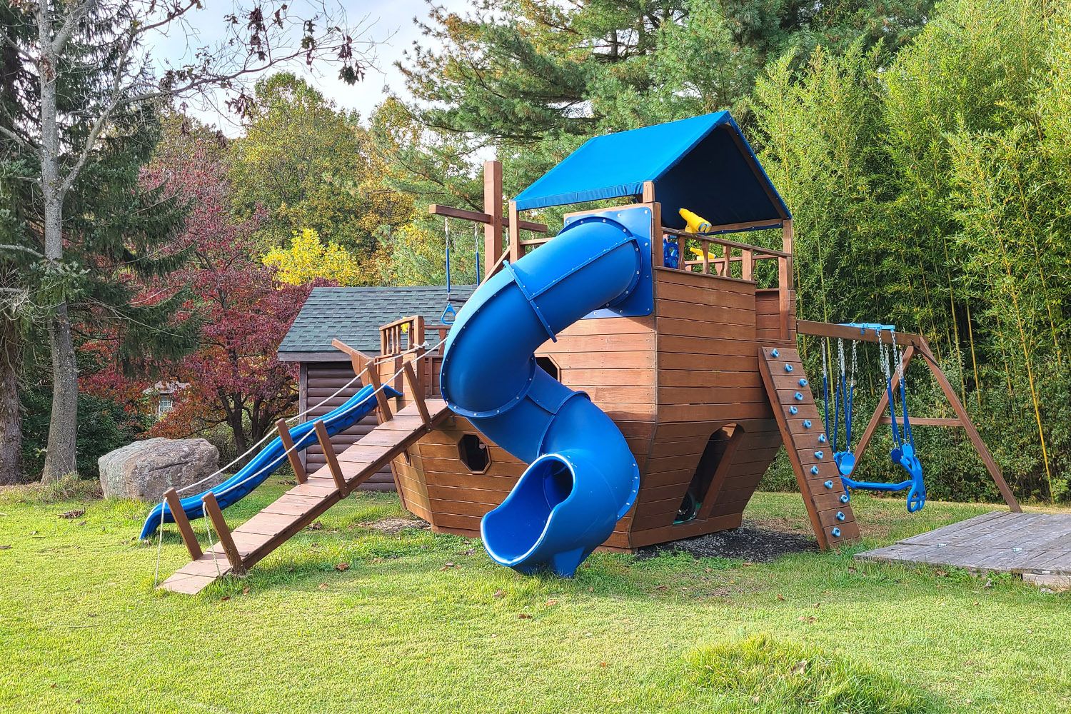 Wooden pirate ship playset with blue slide and swings for kids