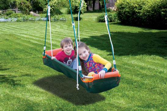 Kids enjoying a boat-style swing set in a lush green backyard.